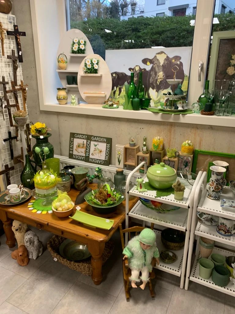 Uitgestalde tuinaccessoires en decoratieartikelen in groene tinten, inclusief potten, dienbladen en plantgerei
