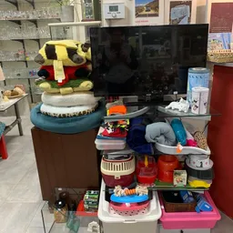 Diverse tweedehands huishoudelijke artikelen en speelgoed op een tafel en standaard in de winkel
