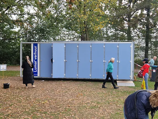 Blauwe mobiele sanitaire unit met Lunarbour-branding in een park met bezoekers