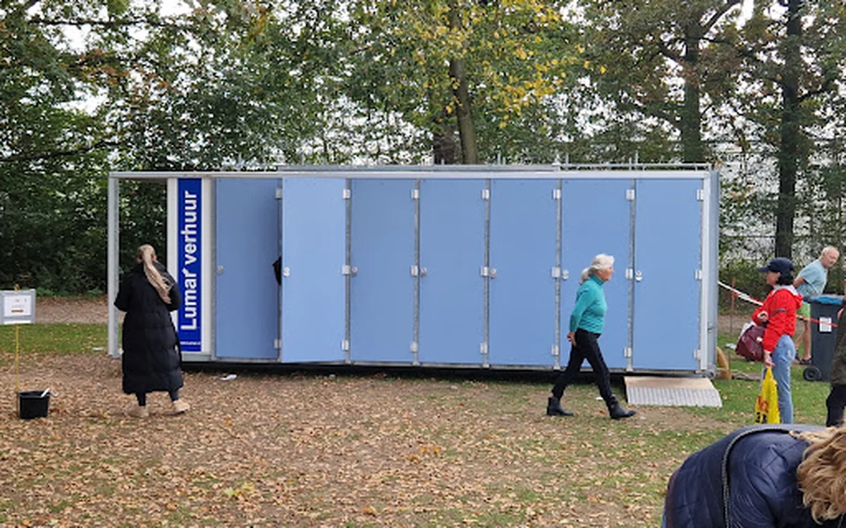 Blauwe mobiele sanitaire unit met Lunarbour-branding in een park met bezoekers