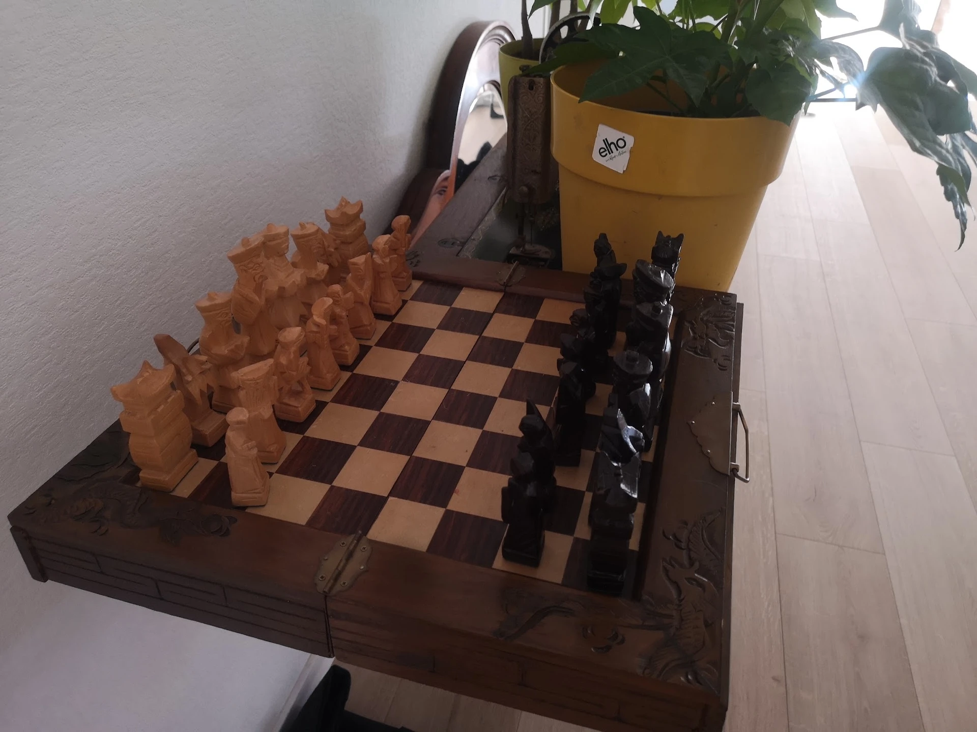 Schaakset op houten tafel met gele bloempot op achtergrond