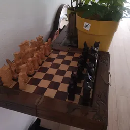 Schaakset op houten tafel met gele bloempot op achtergrond