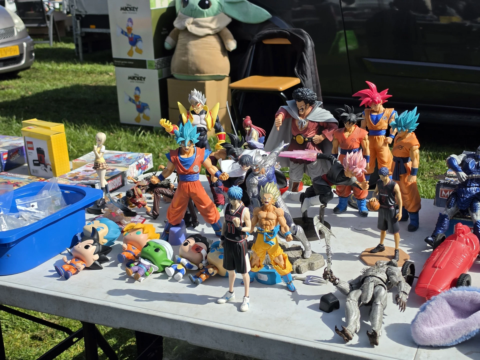 Verzameling speelgoedactiefiguren en collectibles uitgestald op een tafel buiten