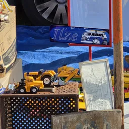 Uitgestalde speelgoedvoertuigen en constructiemodellen op een kraam met blauwe achtergrond