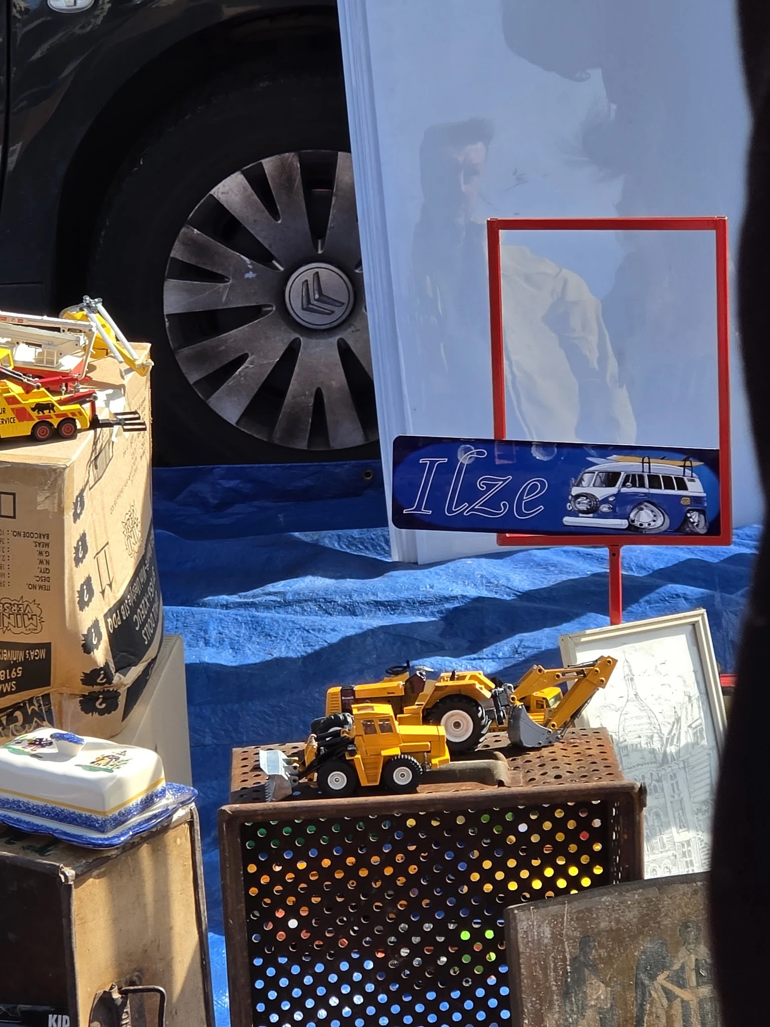 Uitgestalde speelgoedvoertuigen en miniatuurauto's in een vitrine met blauwe achtergrond