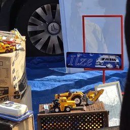 Uitgestalde speelgoedvoertuigen en miniatuurauto's in een vitrine met blauwe achtergrond