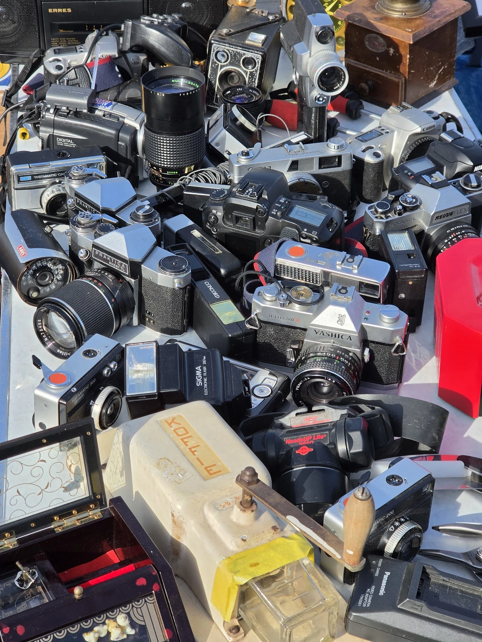Verzameling tweedehands fotocamera's en filmcamera's uitgestald op een witte ondergrond