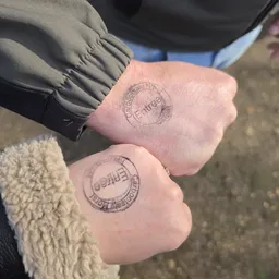 Twee personen tonen hun hand met een stempel van een evenement