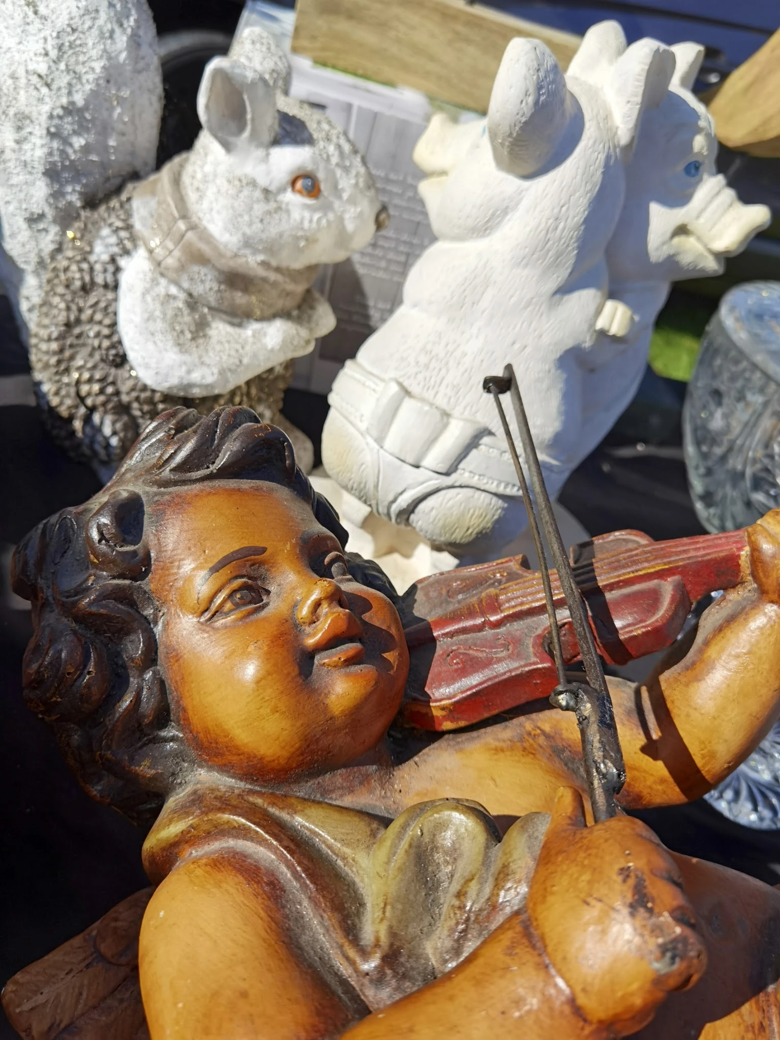 Close-up van een houten beeldje van een engel met viool, met witte decoratieve beelden op de achtergrond