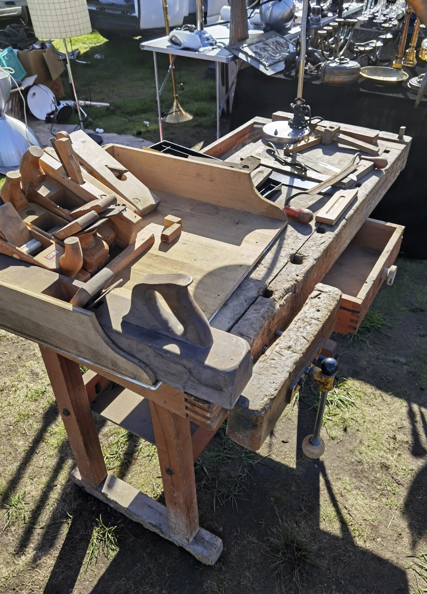 Houten werkbank of tafel met bankschroef, gereedschappen en onderdelen in zonlicht