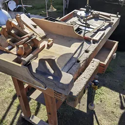 Houten werkbank of tafel met bankschroef, gereedschappen en onderdelen in zonlicht