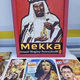 Vintage reclamebord Mekka-likeur naast oude filmposters en boeken in de winkel