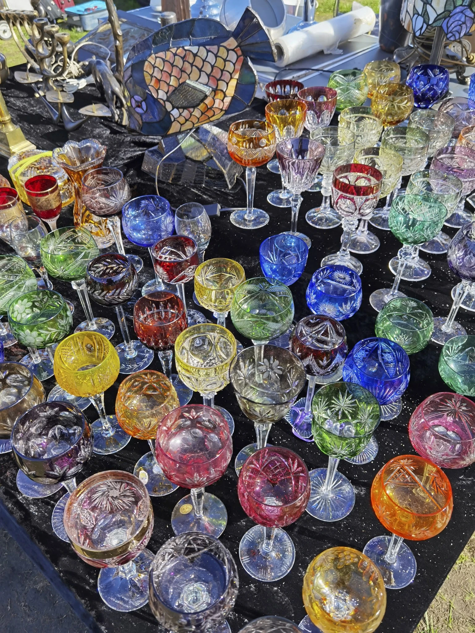 Verzameling gekleurde kristallen glazen en drinkglazen op een zwarte ondergrond