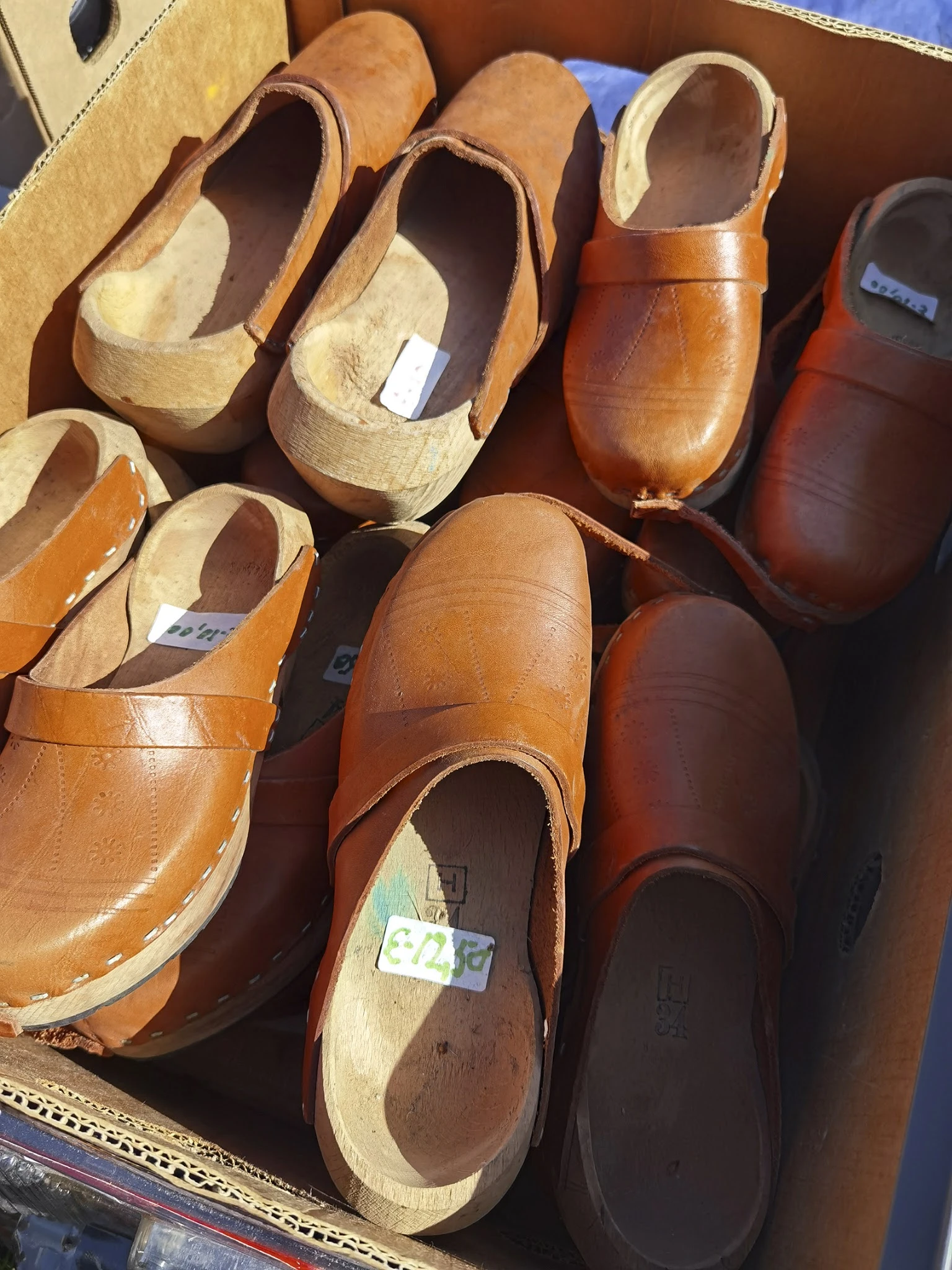 Uitgestalde bruine en beige leren klompen en schoenen op houten vormen