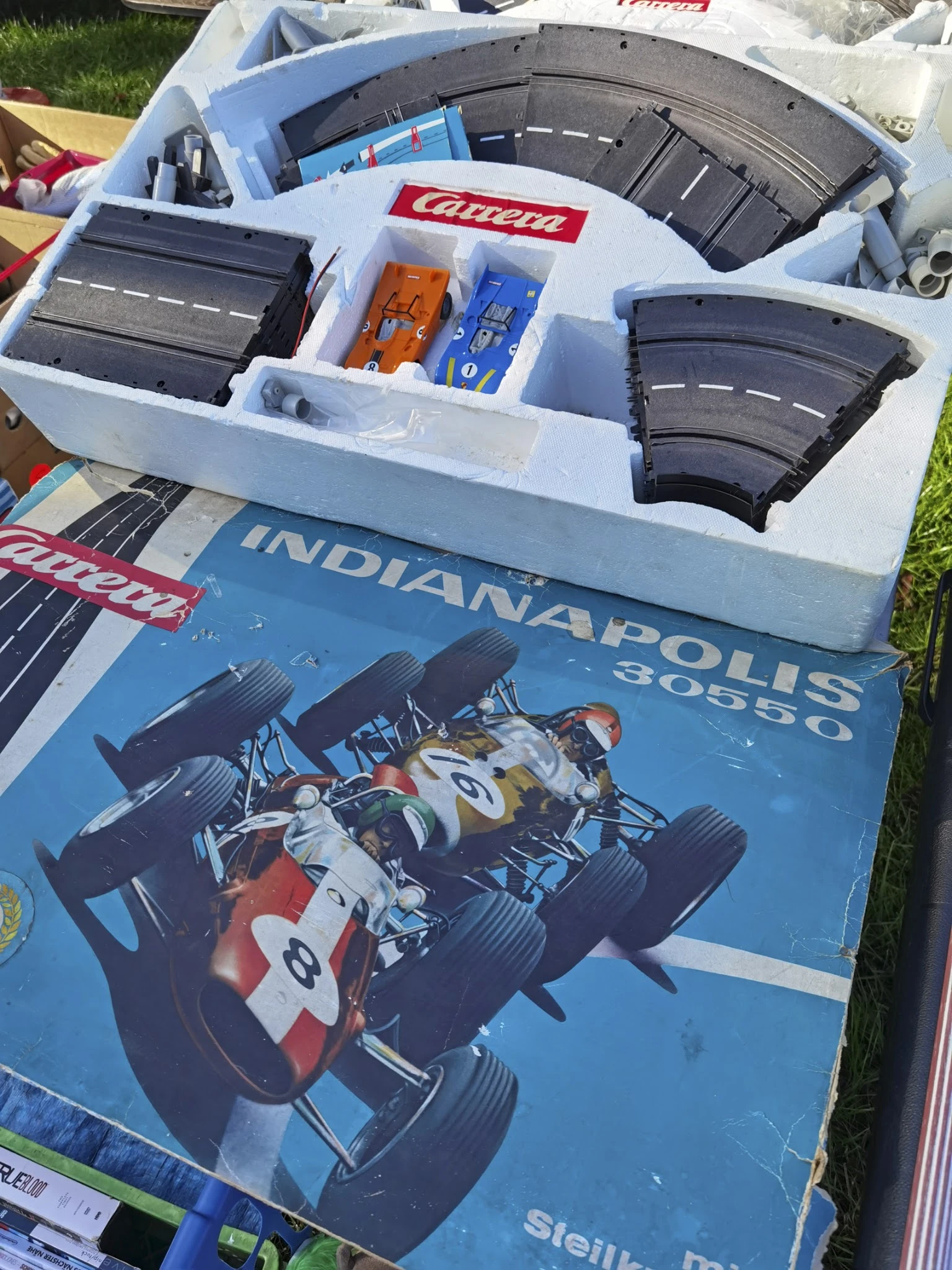 Miniatuurauto's en racebaan onderdelen in een witte opbergdoos