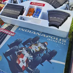 Miniatuurauto's en racebaan onderdelen in een witte opbergdoos