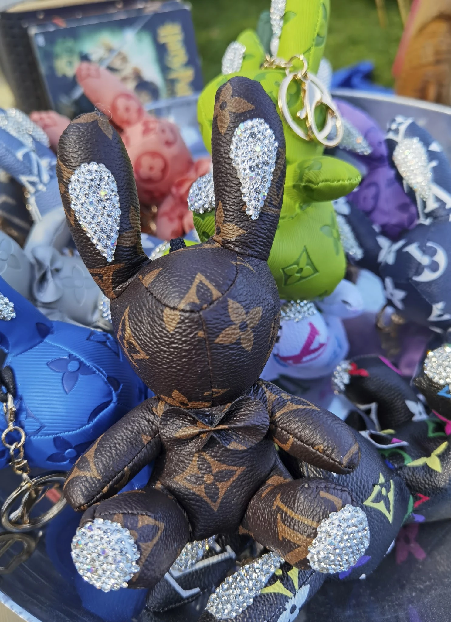 Close-up van een bruine pluchen konijn met glitterdetails en Louis Vuitton-patroon, omgeven door andere gekleurde speelgoedko