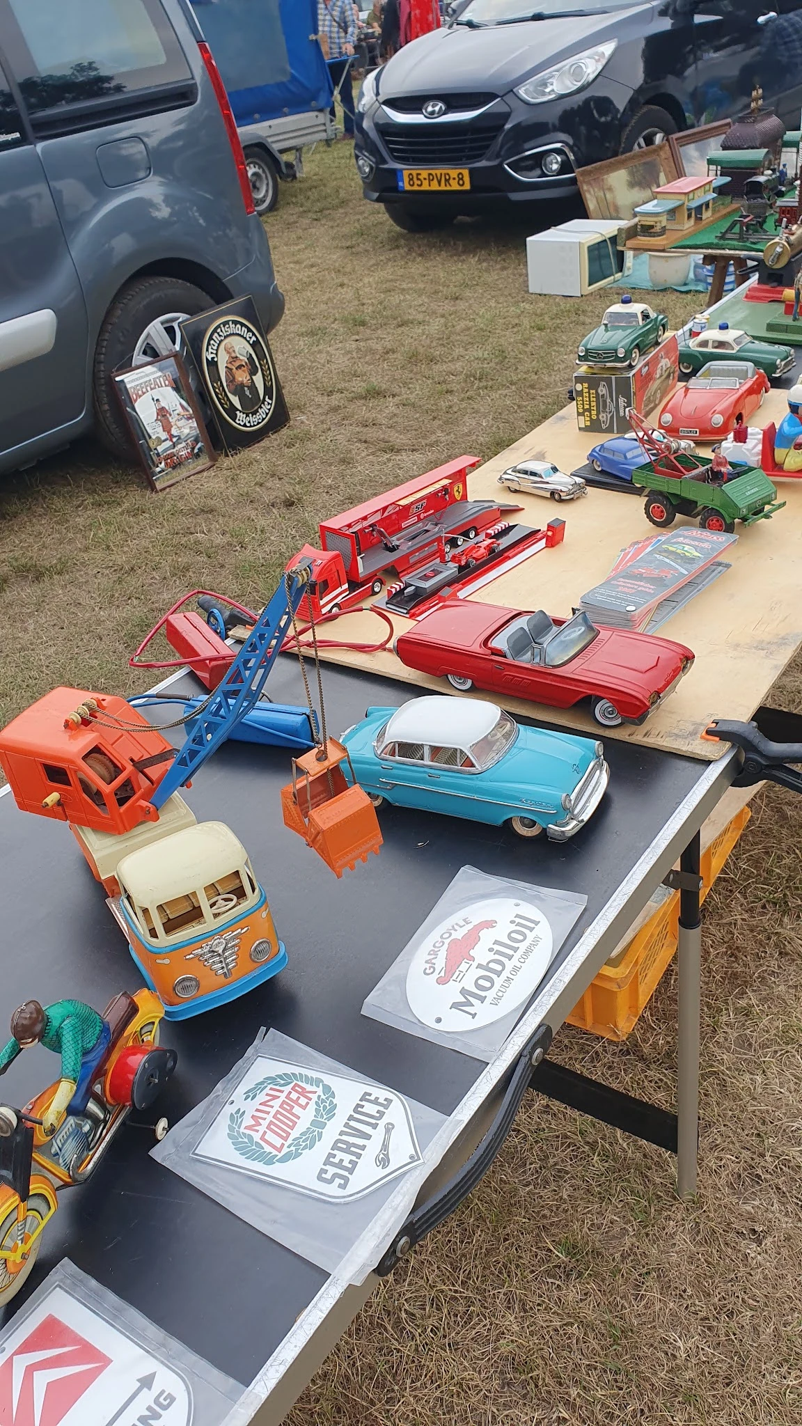 Verzameling speelgoedauto's en voertuigen uitgestald op een tafel, waaronder een rode brandweerwagen, blauwe kraan, turquoise
