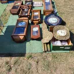 Verzameling tweedehands wandklokken en klokken in verschillende stijlen en maten op display