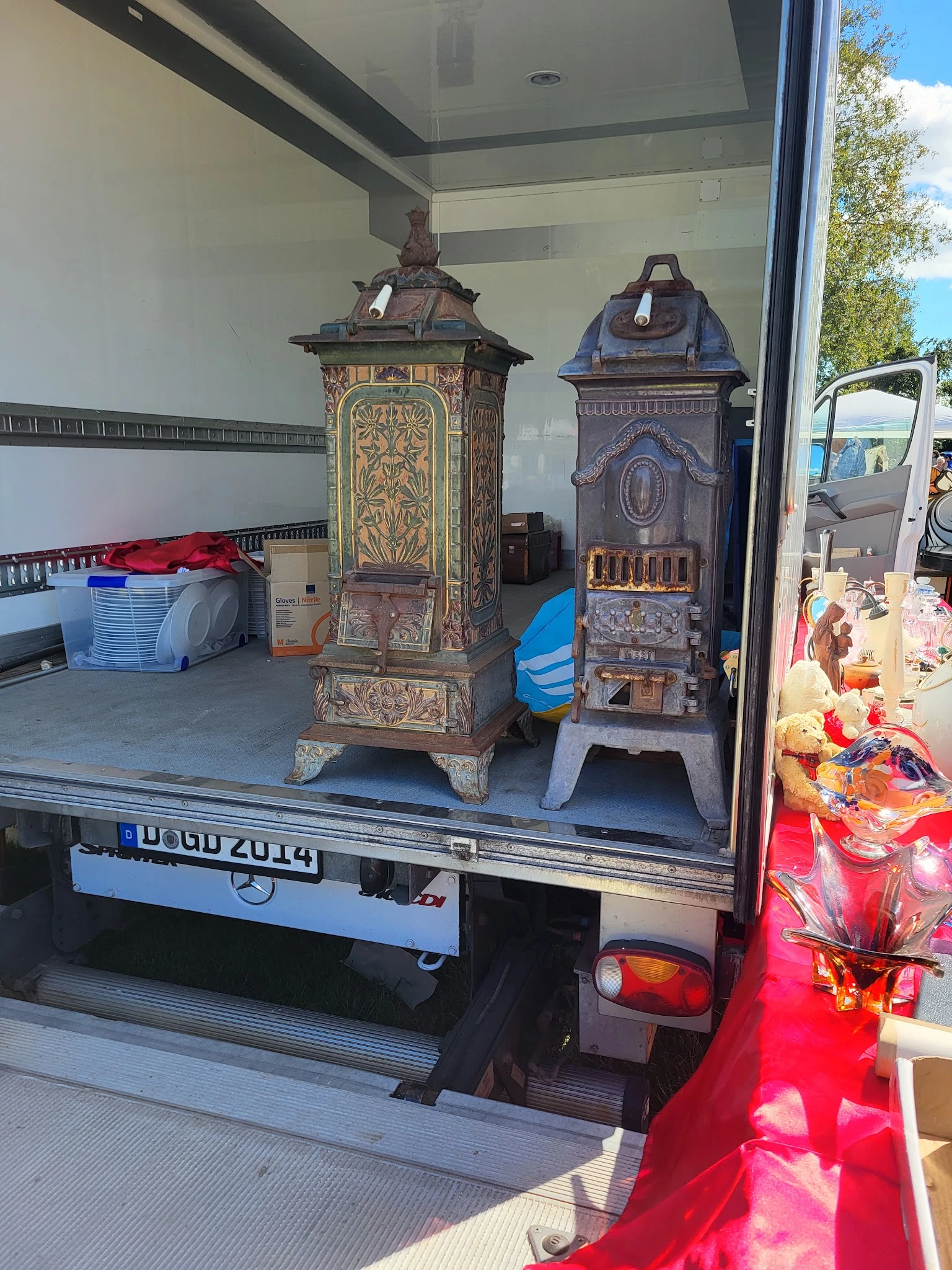 Twee antieke kachels met decoratieve details op het laadplatform van een bestelwagen