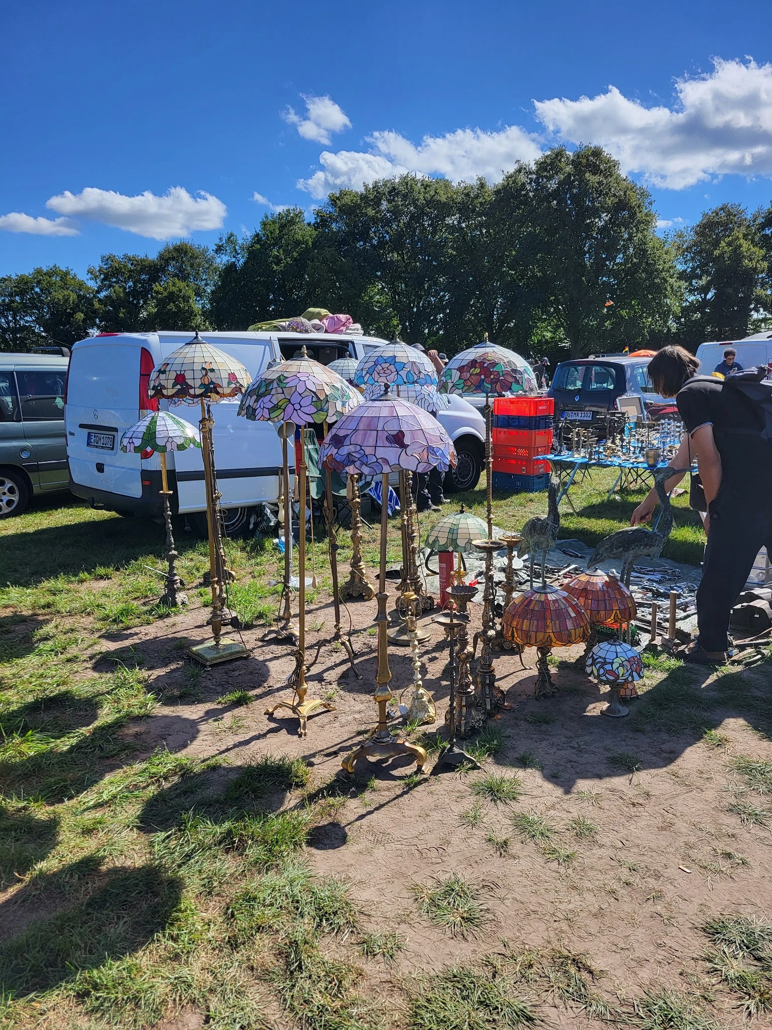 Tweedehands artikelen uitgestald op een carbootsale, met paraplu's, stoelen en ander huishoudelijk spul