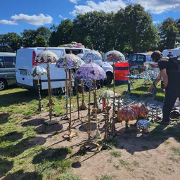Tweedehands artikelen uitgestald op een carbootsale, met paraplu's, stoelen en ander huishoudelijk spul