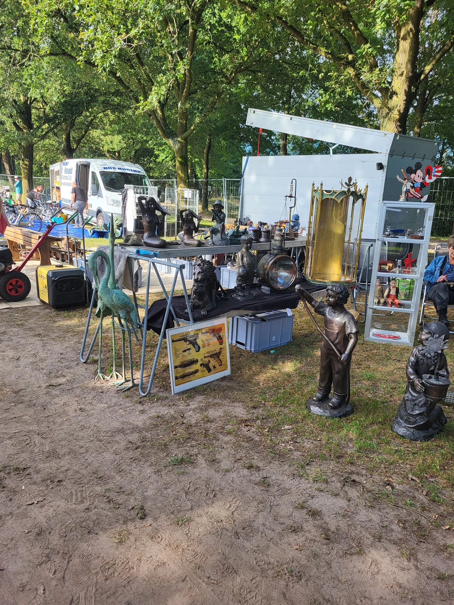 Kraampje op carbootsale met diverse gebruiksartikelen, beelden en meubels uitgestald op en rond een tafel