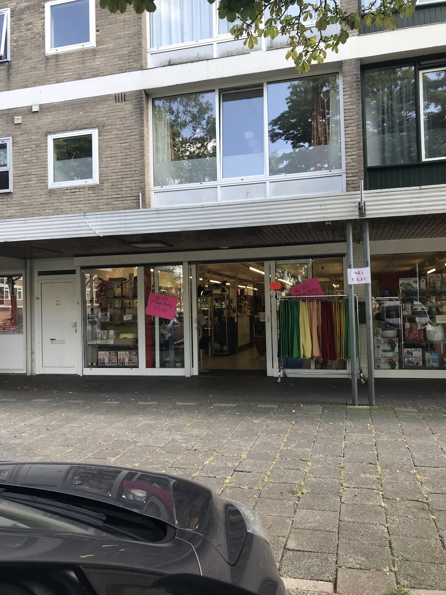 Winkelgevel met uitstalramen vol kleding en accessoires, magenta roze decoratieve elementen in de etalage