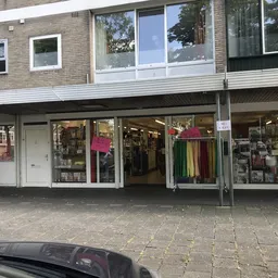 Winkelgevel met uitstalramen vol kleding en accessoires, magenta roze decoratieve elementen in de etalage