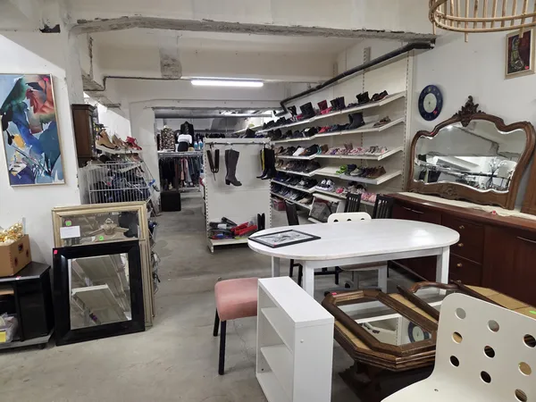 Winkelvloer van kringloopwinkel met diverse meubels, rekken met kleding en accessoires