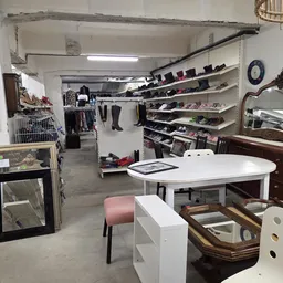 Winkelvloer met rekken kleding, schappen met accessoires en meubelstukken, ronde tafel in het midden