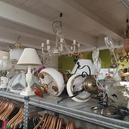 Uitgestalde lampen, kroonluchters, servies en decoratieve items op een tafel in de winkel