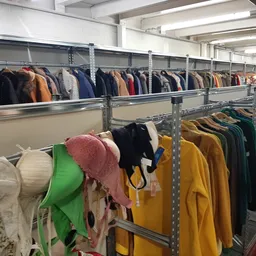 Metalen stellingen met uiteenlopende tweedehands kleding in verschillende kleuren en stijlen