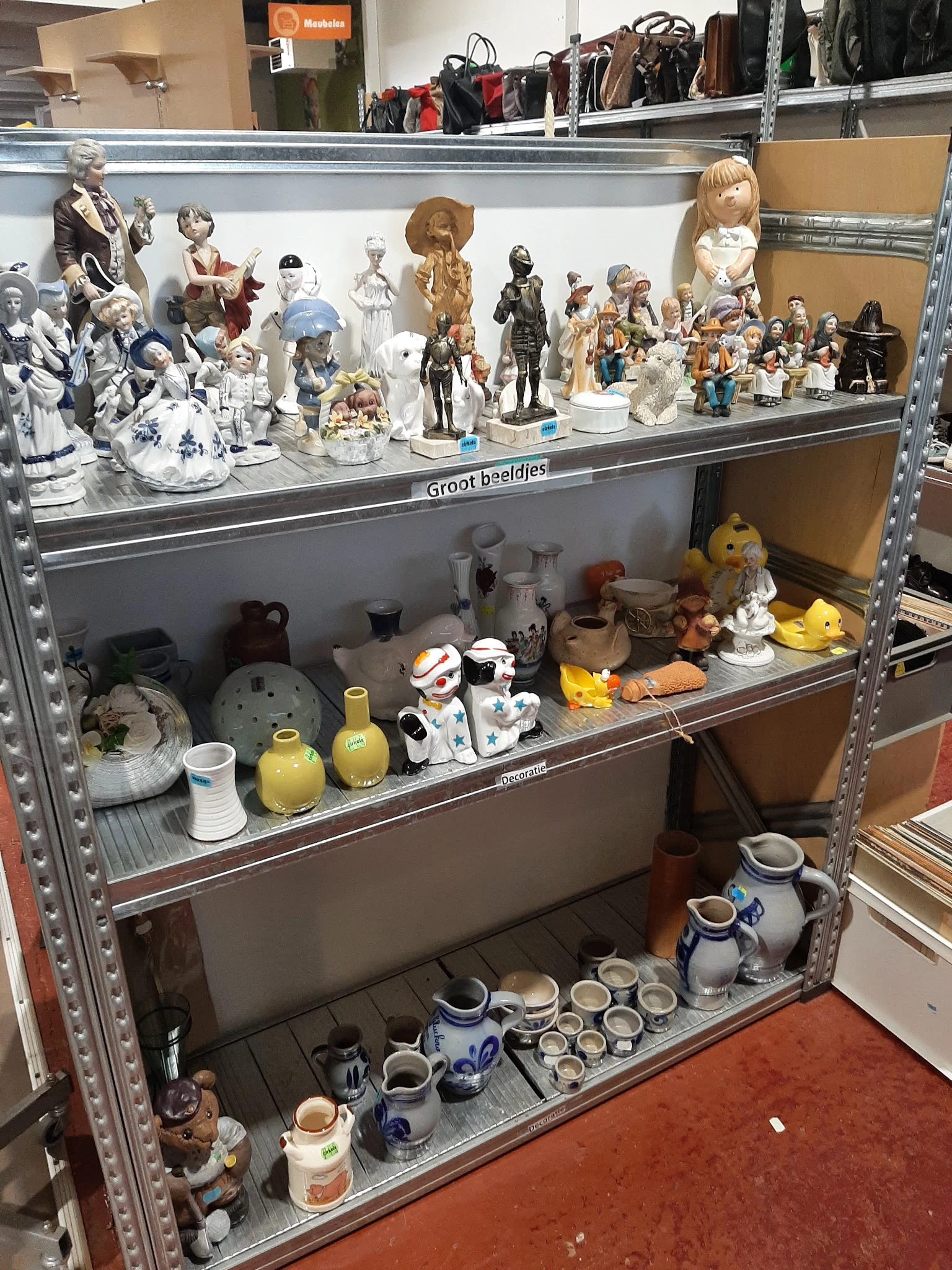 Stellingkasten met porselein, beeldjes, vazen en decoratieve artikelen in een kringloopwinkel