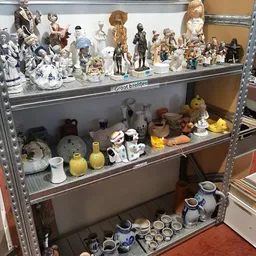 Stellingkasten met porselein, beeldjes, vazen en decoratieve artikelen in een kringloopwinkel