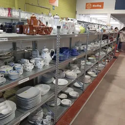 Stellingen met serviesgoed, borden, kopjes en aardewerk in verschillende kleuren en stijlen