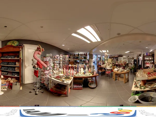 Winkelvloer met stellingen en uitgestalde kerstdecoratie, huishoudartikelen en diverse spullen onder gebogen plafond met dakl