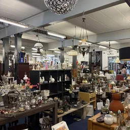 Overzicht van de winkelvloer met diverse gebruikte spullen, meubels, lampen en decoratieve items uitgestald