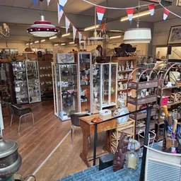 Ruim winkelinterieur met stellingen, toonbanken en diverse koopwaar, versierd met vlaggen