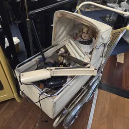 Vintage kinderwagen met pop erin, witte en blauwe kleuren, geopend om inhoud te tonen