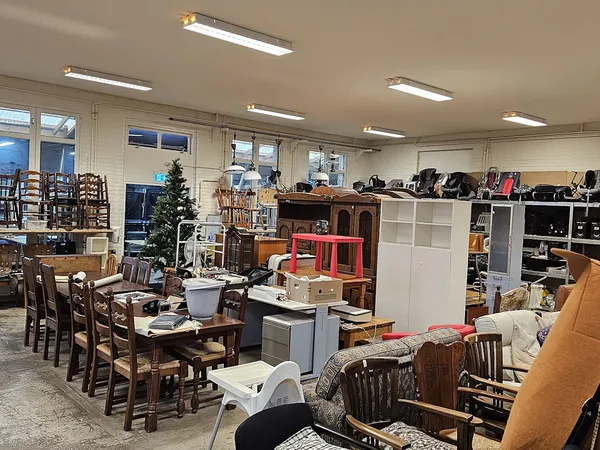 Ruim winkelinterieur met houten eettafels, stoelen, kasten en diverse meubels en huishoudartikelen uitgestald