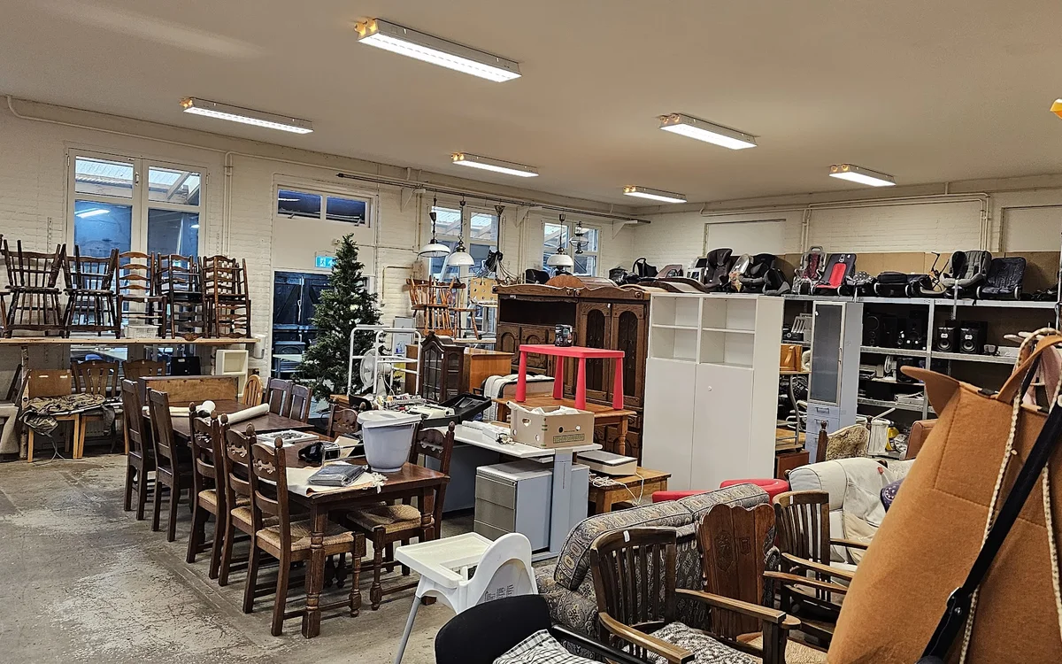Ruim winkelinterieur met houten eettafels, stoelen, kasten en diverse meubels en huishoudartikelen uitgestald