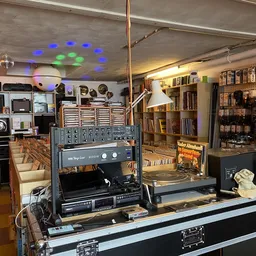 Winkelbinnenkant met vintage audio-apparatuur, versterkers, platen en boeken op stellingen, blauwe verlichting aan plafond
