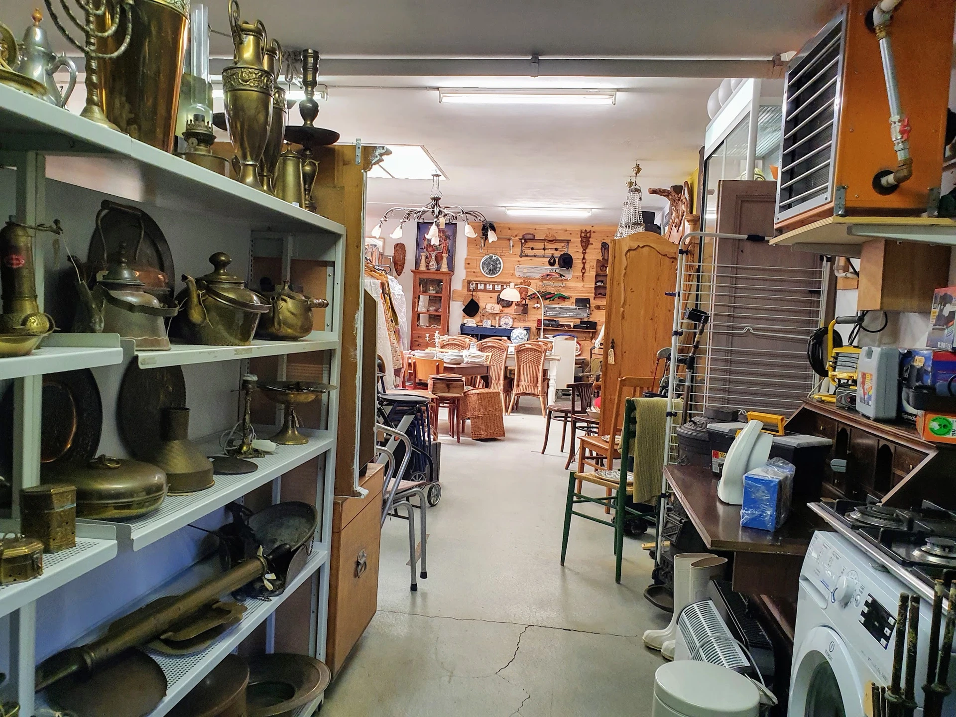 Winkelvloer met stellingen vol huishoudspullen, kookgerei en bric-à-brac in een tweedehandswinkel