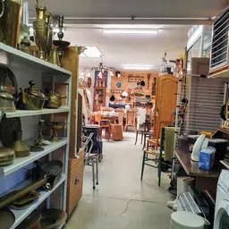 Winkelvloer met stellingen vol huishoudspullen, kookgerei en bric-à-brac in een tweedehandswinkel