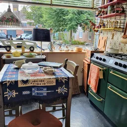 Vintage winkelbinnenruimte met tafel met kleed, stoelen, groene retro-oven en houten stellingen met antieke spullen