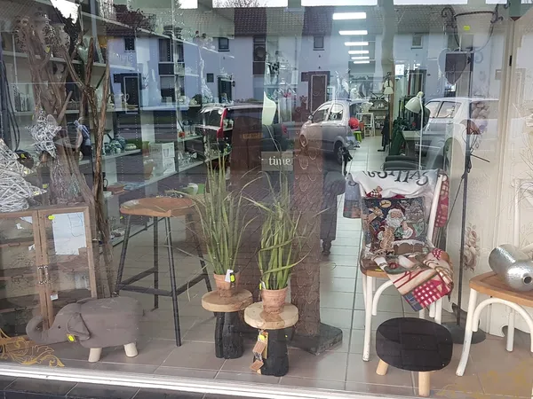 Winkelraam met uitgestalde decoratievoorwerpen zoals plantenpotten, krukken, stoelen en andere huishoudartikelen