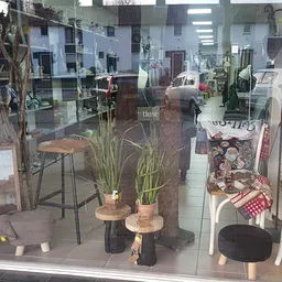 Winkelraam met uitgestalde decoratievoorwerpen zoals plantenpotten, krukken, stoelen en andere huishoudartikelen