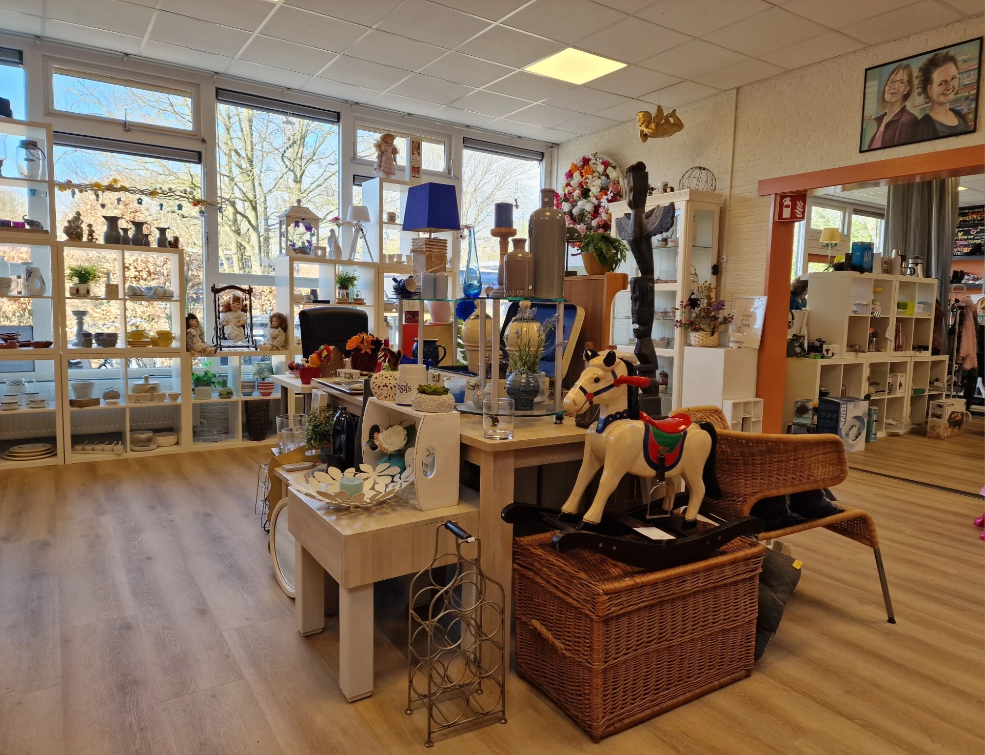 Heldere winkelvloer met diverse uitgestalde tweedehands artikelen, lampen, decoraties en meubels, grote ramen met uitzicht na