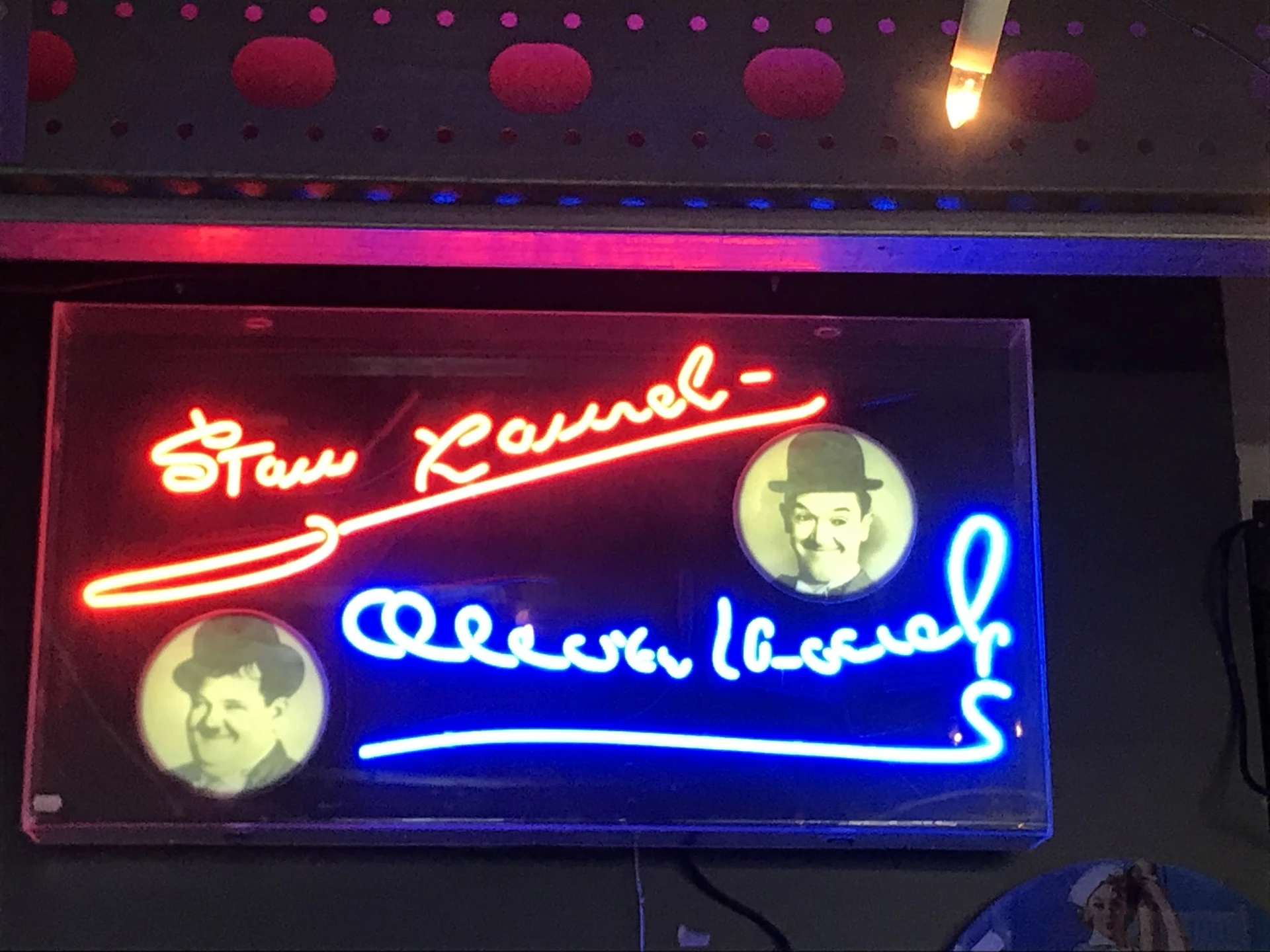Neonreclame met rode en blauwe letters en twee portretten in gele cirkels